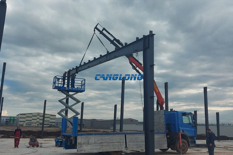 Truck-mounted crane lifting a steel rafter during industrial plant construction in Skopje, North Macedonia
