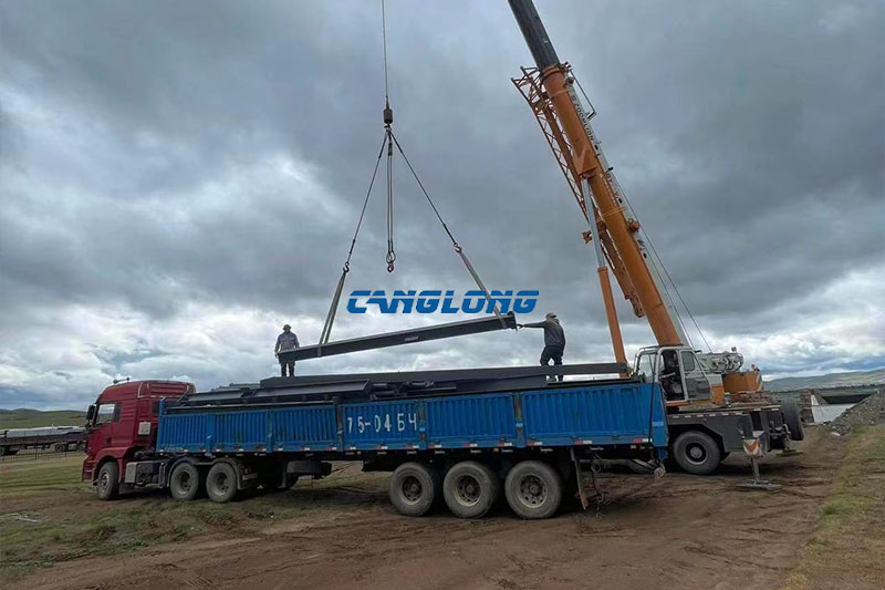 Steel structure materials being unloaded and handled on site during erection of a mining workshop in Mongolia