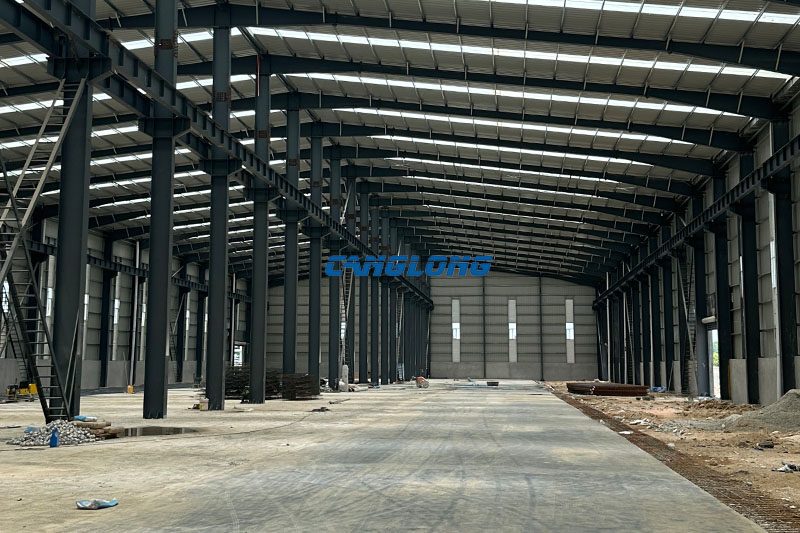 Wide interior view of the 184 m by 42 m Bangkok industrial plant, showing both spans of the Q355B frame, floor slab and finished envelope