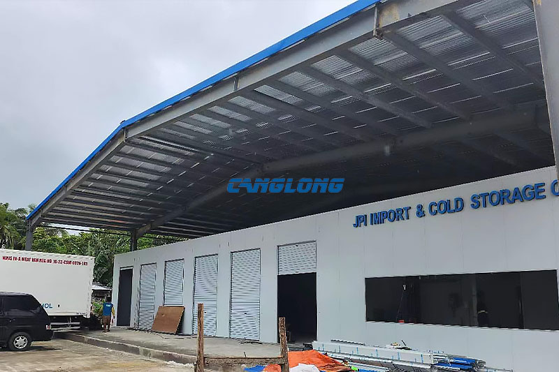 Open-sided cold room shed in Cebu, Philippines — insulated color-steel roof on a painted H-section frame, with white panel cold rooms, roller doors and a refrigerated truck at the loading bay