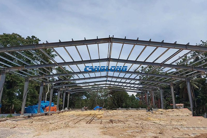 Painted grey H-section portal frames of the Cebu cold room shed during erection, standing on the open site before roofing